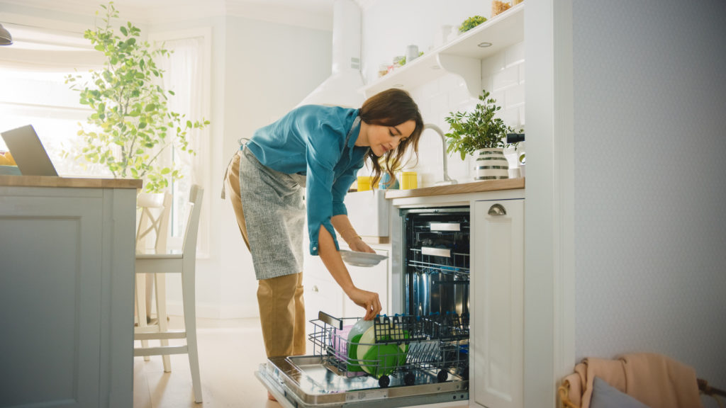 Woman loading dishwasher in her kitchen.