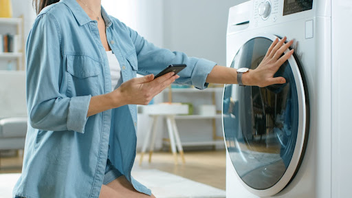 Homeowner looking at phone while shopping for new washer and dryer set.