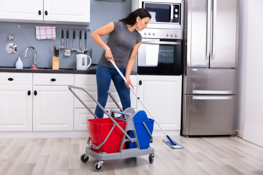 Homeowaner mopping kitchen floors because refrigerator is leaking water