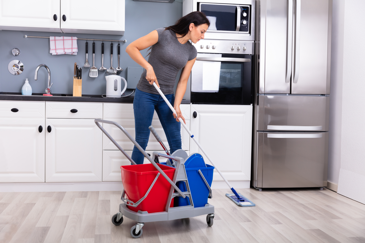 Homeowaner mopping kitchen floors because refrigerator is leaking water