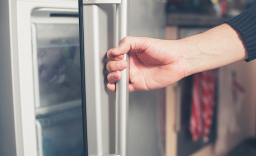 A hand opening a freezer door.