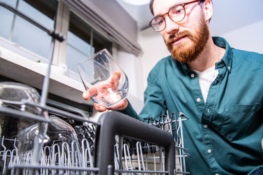 A man inspecting a glass that was cleaned in a dishwasher.