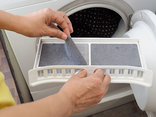 Hand removing dryer lint from lint trapper.