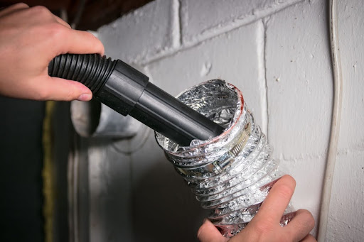 Homeowner using vacuum to suck lint out of dryer vent.